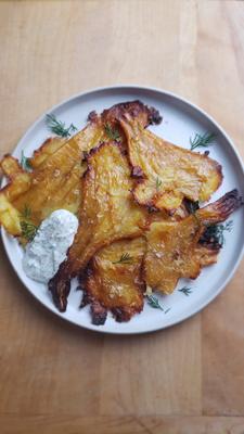 Golden, crispy parsnip tostones arranged on a plate, served with a creamy Lemon Dill Yogurt sauce, garnished with fresh herbs.