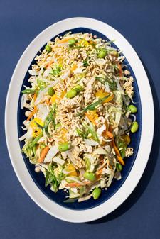 A colorful ramen noodle crunch salad with shredded cabbage, carrots, edamame, mandarin slices, pickled daikon, and crushed ramen noodles tossed in a creamy miso-tahini dressing.